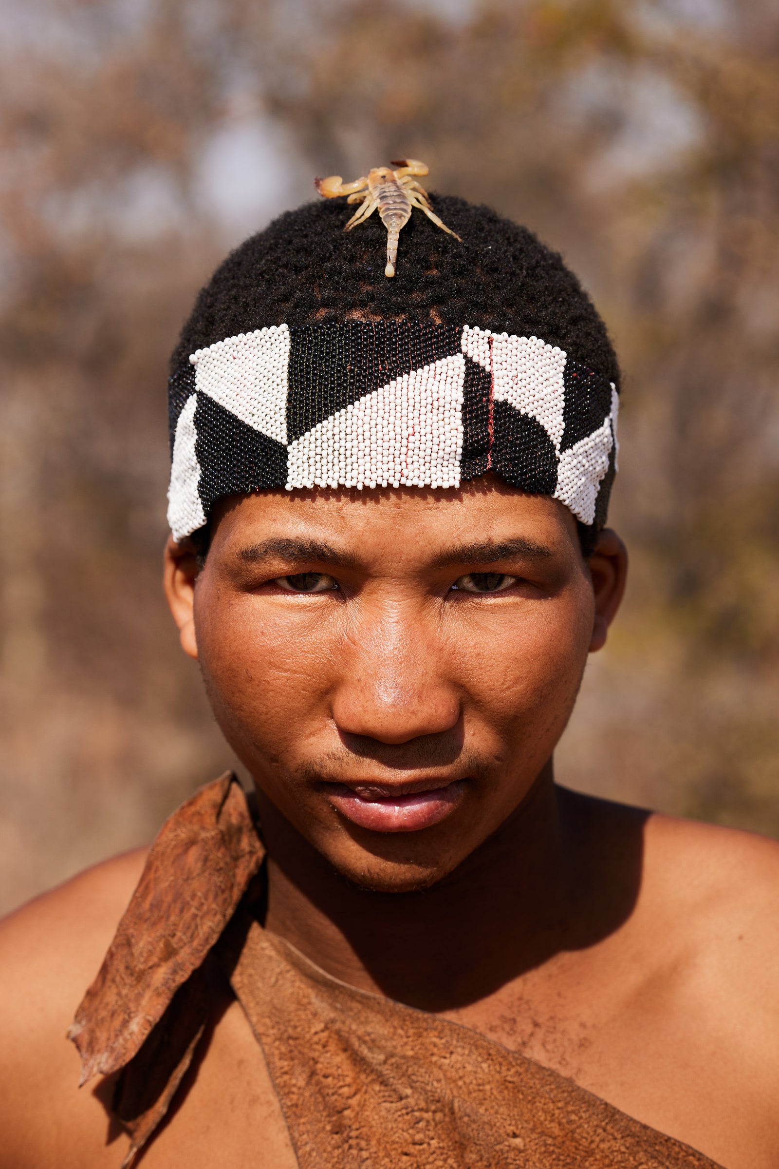 Portrait of a young San Bushman wearing a black and white beaded headband with a scorpion perched on top